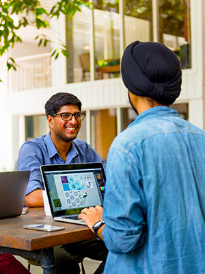 two youngsters discussing and working on laptop computers